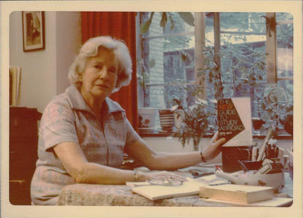 Older woman showing off a book at a desk