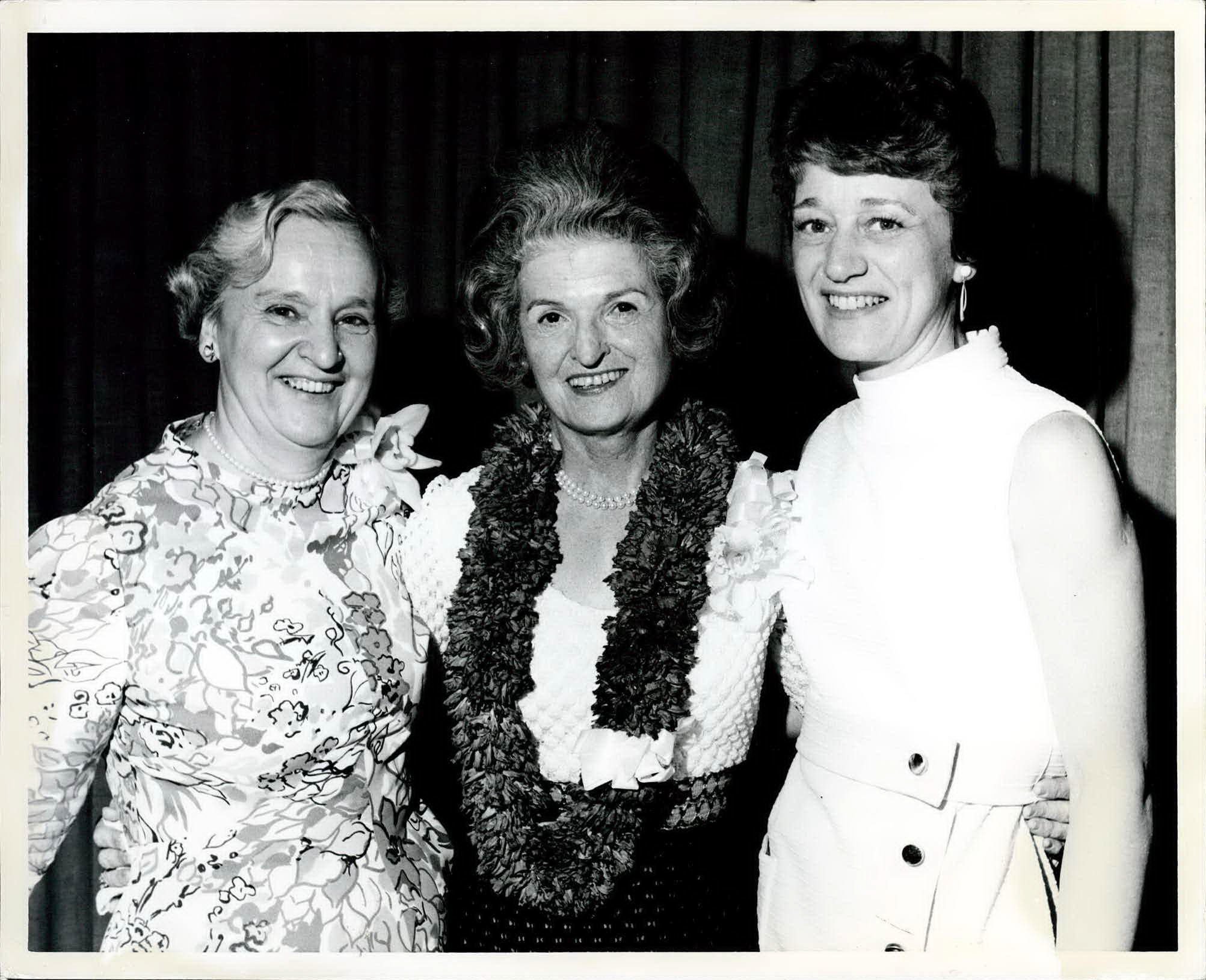 Black and white image of three women smiling at a party