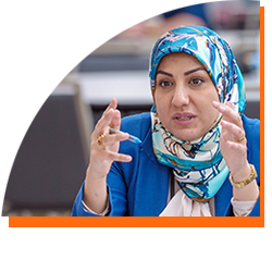 A woman wearing a hijab speaks to a group of people