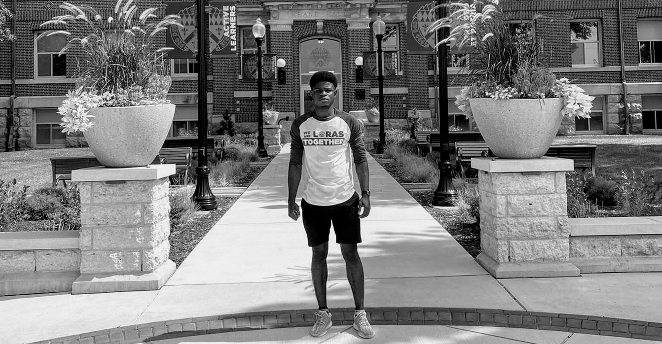 Student standing in front of a building on campus