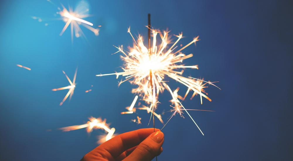 Hand holding a sparkler against a blue background
