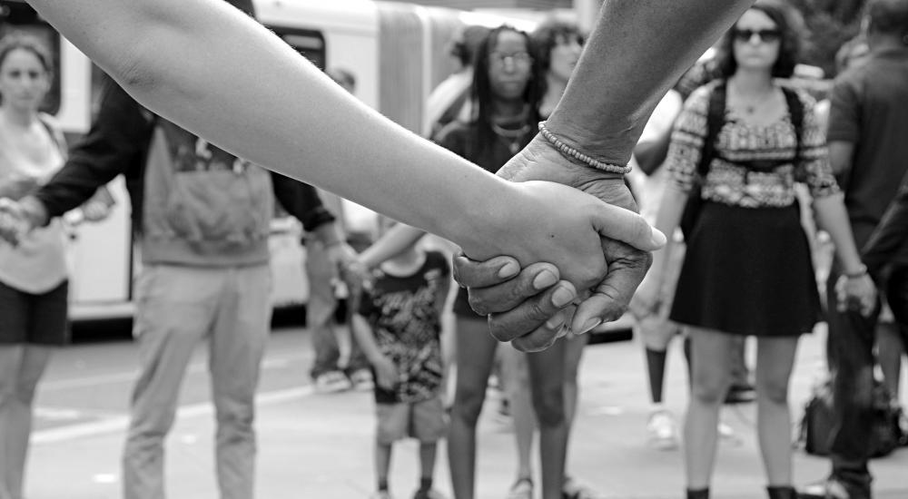 black and white photo of people holding hands at a protest.