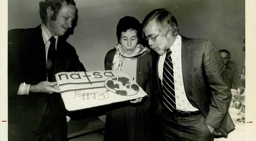 Photograph of someone blowing candles on a NAFSA cake