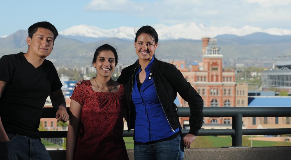 three students with a college campus in the background