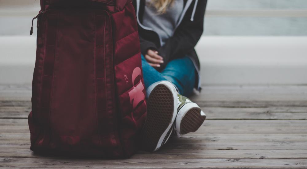 girl sitting on the ground with a backpack