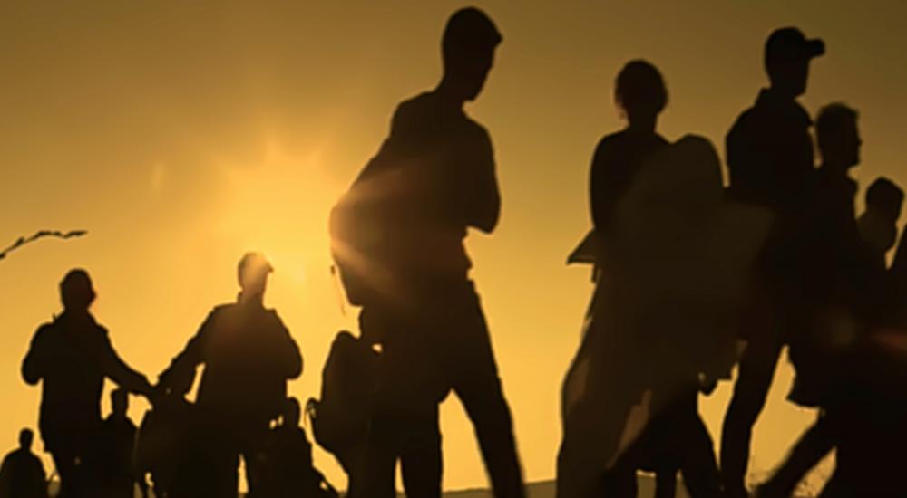 Silhouettes of people walking across a field
