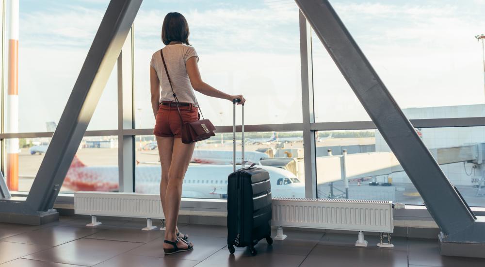 Student waiting at the airport with luggage