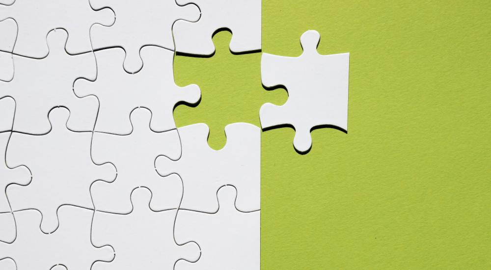 one puzzle piece to the side of partially finished puzzle
