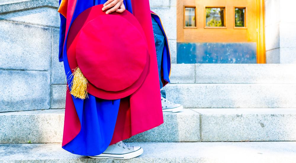 Person in a graduation gown holding a tam