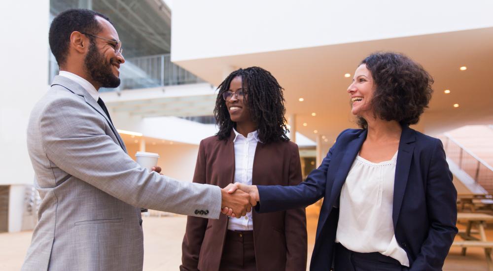 Three people, two are shaking hands