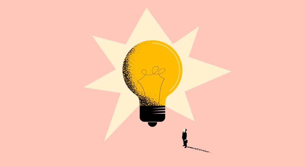 small figure stands looking up at big light bulb