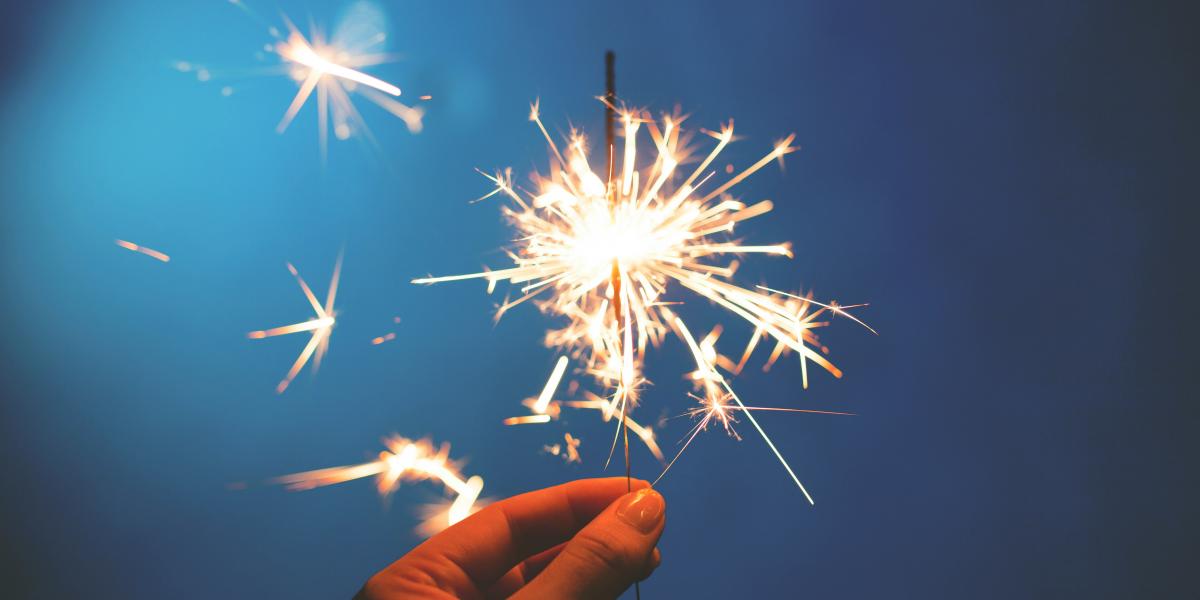 Hand holding a sparkler against a blue background