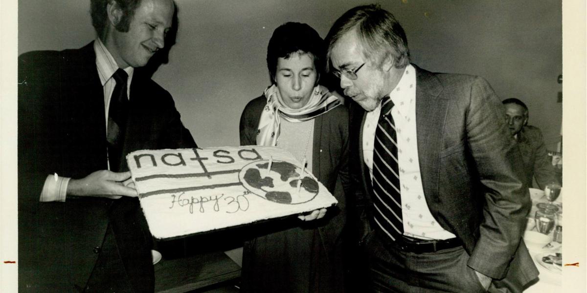 Photograph of someone blowing candles on a NAFSA cake