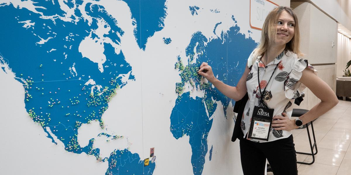 woman putting a pin on a large wall map