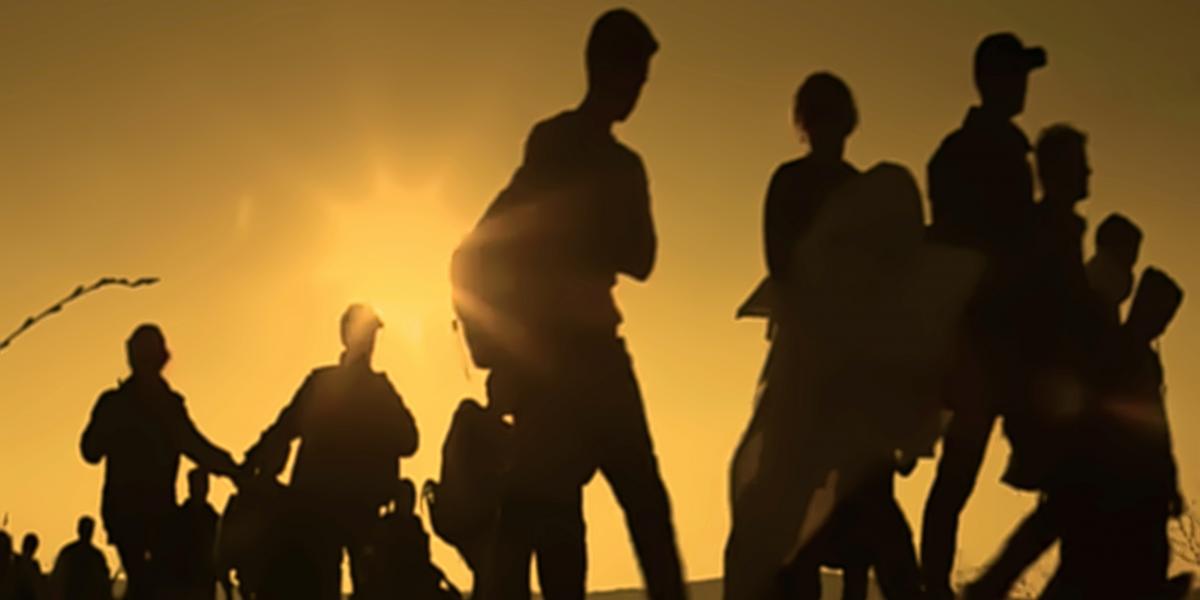 Silhouettes of people walking across a field
