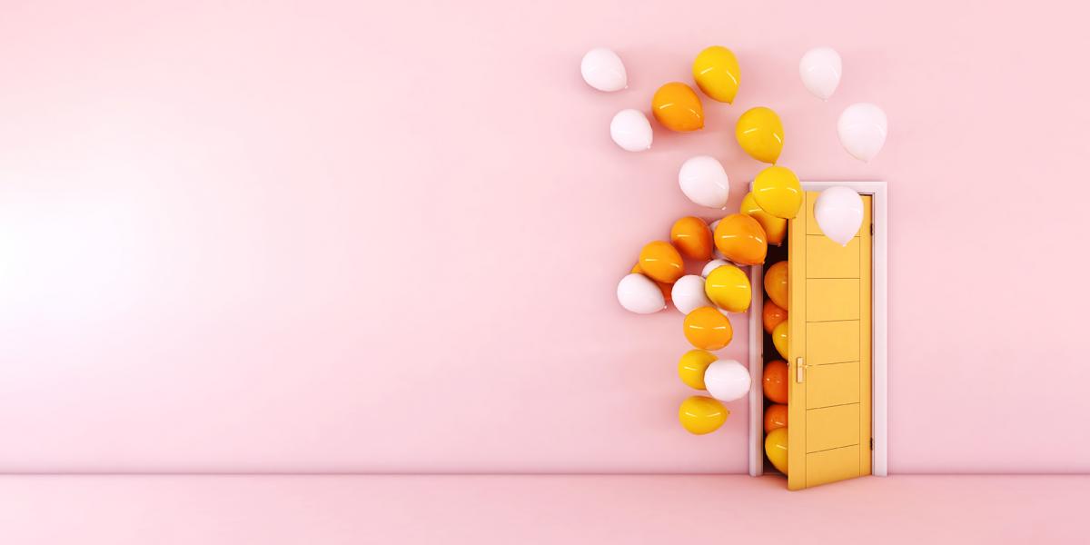 yellow and white balloons emerging from yellow door in pink room