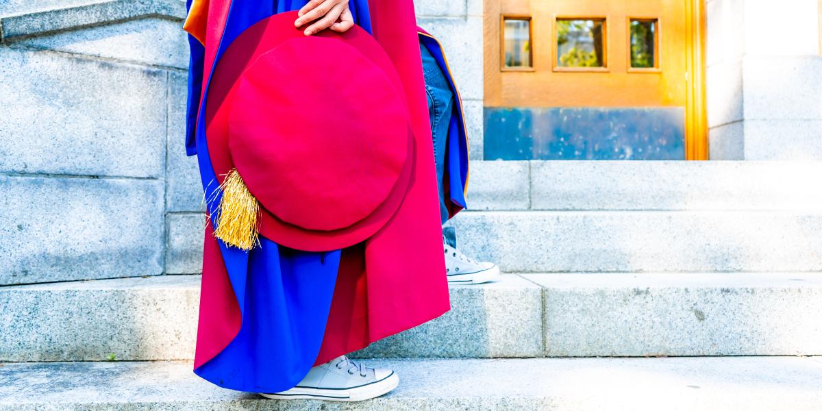 Person in a graduation gown holding a tam