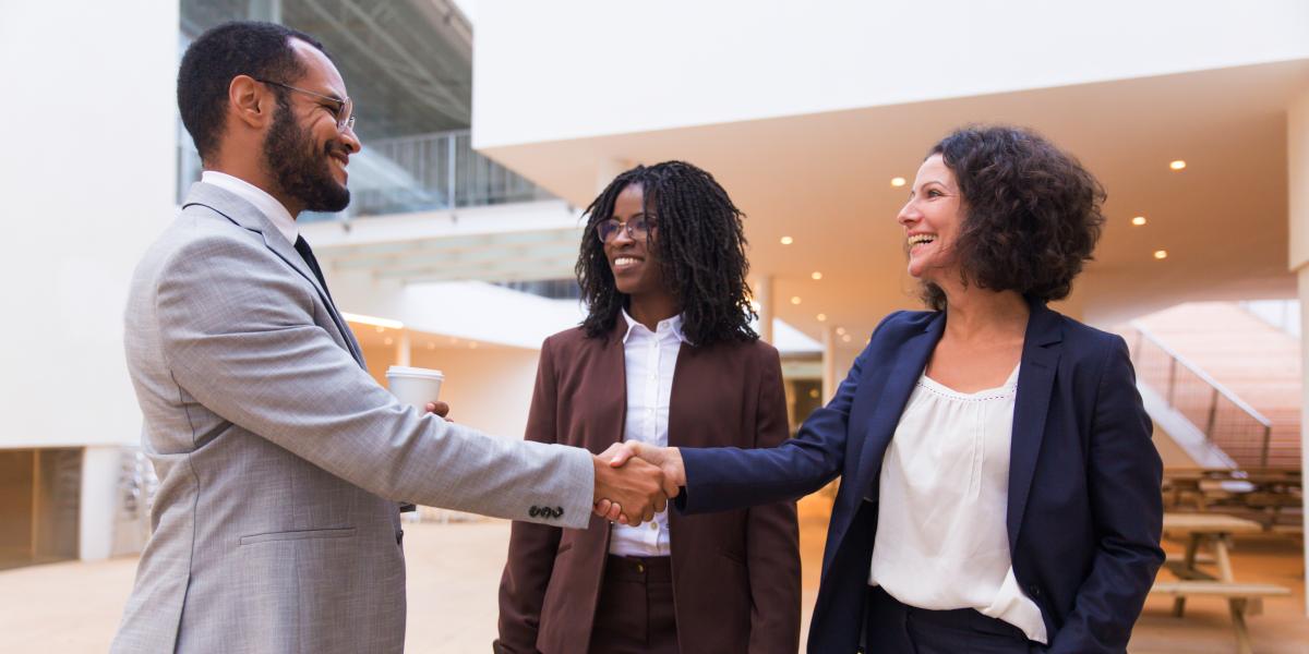 Three people, two are shaking hands