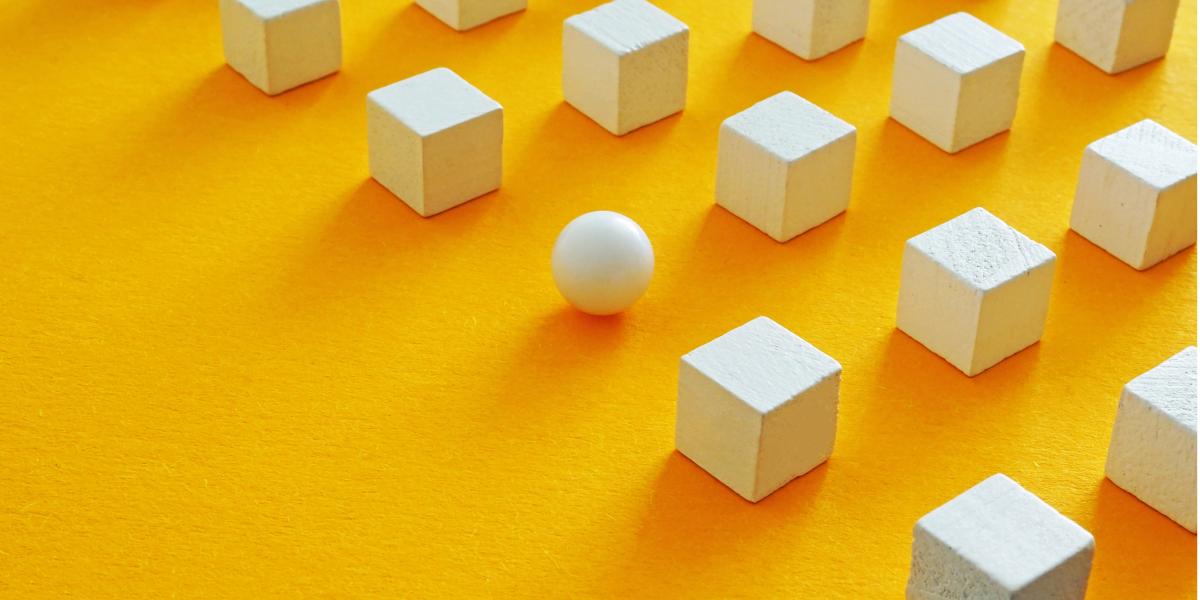 wooden blocks and one sphere in grid pattern on orange background