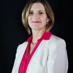 a women with dirty blonde hair, slightly shorter than shoulders, wearing a white blazer and a pink shirt