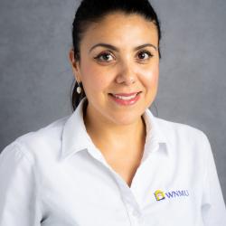 Brenda smiles in front of a gray background wearing a white polo shirt