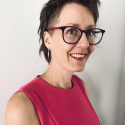 Headshot photo of a smiling woman with glasses