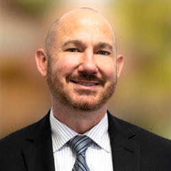 Man wearing a suit and tie in front of a blurred background