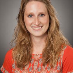 Whitney smiles, wearing an orange patterned shirt