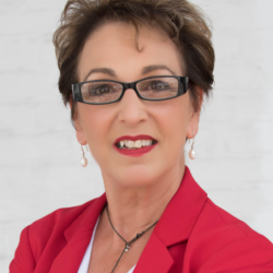 Professional headshot of a woman will glasses and short hair