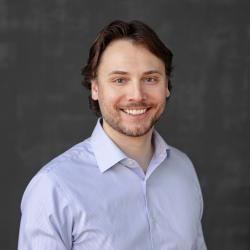 Josh smiles in front of a grey background