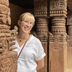 woman in Nepal smiling at camera from behind a pillar