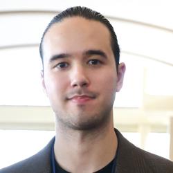 Nick smiles in a suit jacket