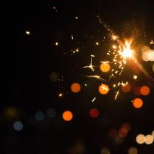 Hand holding a sparkler against a black background