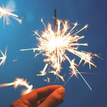 Hand holding a sparkler against a blue background