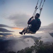 A student paraglides over rainforest