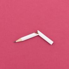 broken white pencil on pink background