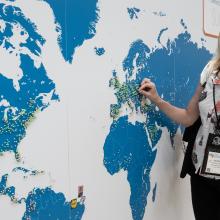 woman putting a pin on a large wall map