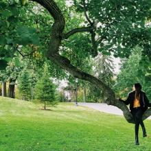 Photo of a student sitting on a brach of a tree
