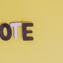 "VOTE" cutout letters on yellow background