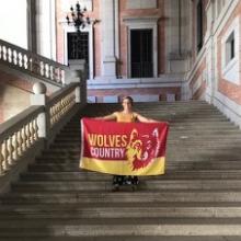 A student standing on a staircase with a banner from her school.