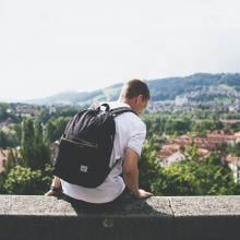 student sitting on a wall overlooking a city