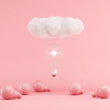 illuminated lightbulb and cloud floating above pink lightbulbs on pink ground