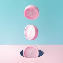 pastel pink wall clocks on blue backdrop falling down