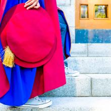 Person in a graduation gown holding a tam