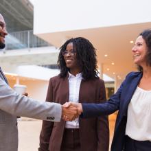 Three people, two are shaking hands