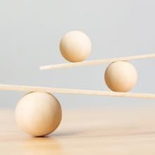 Three wooden balls balancing on two planks 