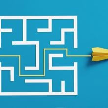 yellow paper airplane makes path through labyrinth