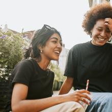 two smiling young women sit on steps
