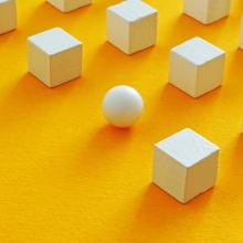 wooden blocks and one sphere in grid pattern on orange background